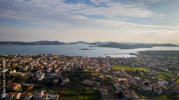 Fototapeta Panoramic aerial view of Cunda Island (Alibey Island) and nearby Aegean islets in Ayvalik, Turkey, showing traditional houses, green fields, harbor, and calm blue sea under soft afternoon light.