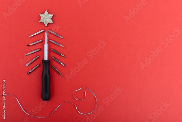 Fototapeta Screwdriver and bits arranged as christmas tree with glitter star on red background. Creative concept of festive spirit and craftsmanship in minimalist style. Copy space
