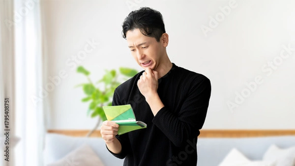 Obraz 通帳を見て考える男性