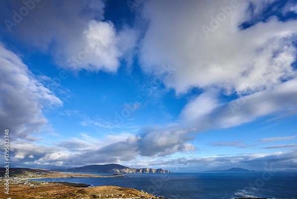 Fototapeta View over the ocean in cloudy blue sky weather with Achill island, Keel vilage and beach