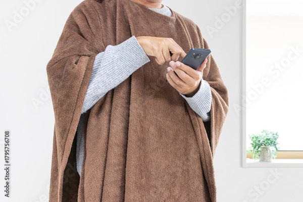 Obraz 着る毛布を着てスマートフォンを使う男性（30代、日本人、顔無し）