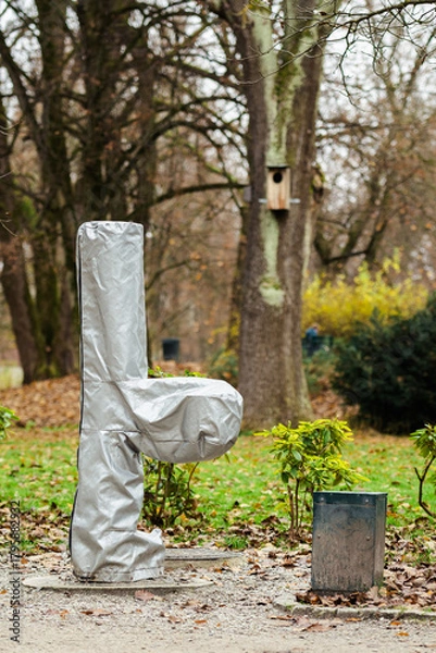 Fototapeta Fountain in a park covered with a protective plastic wrap to shield it from frost and cold winter temperatures