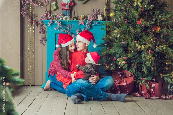 Fototapeta Happy family celebrates Christmas. Mom, Dad and Son in Christmas Decorations