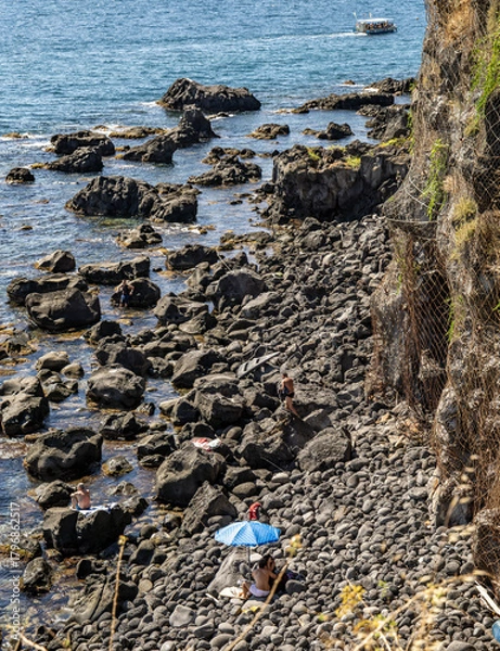 Fototapeta Looking down onto the volcanic beach of Aci Castello, just north of Catania, Sicily, known for its stunning coastal views, rocky shores, and historical landmarks