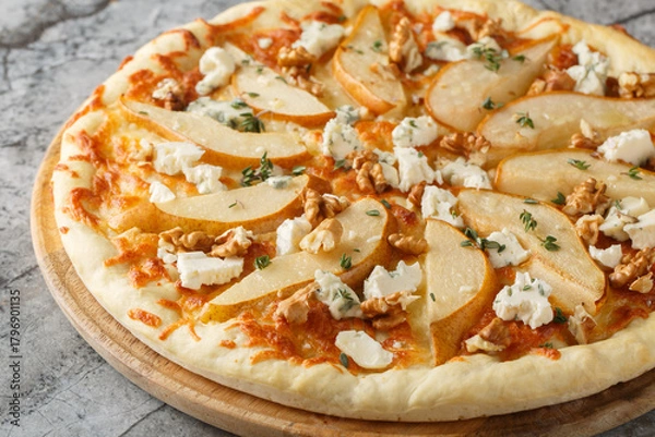 Obraz Honey pear pizza with blue cheese, nuts, mozzarella and thyme close-up on a wooden board on the table. Horizontal