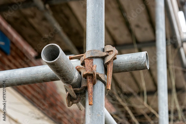 Obraz two steel scaffolding pipes cross each other and are secured with anchors