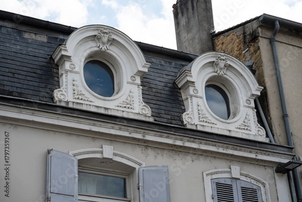 Fototapeta The intricate design of two circular windows on a building showcases ornate details against a blue sky. Sunlight highlights the craftsmanship of this historic structure.
