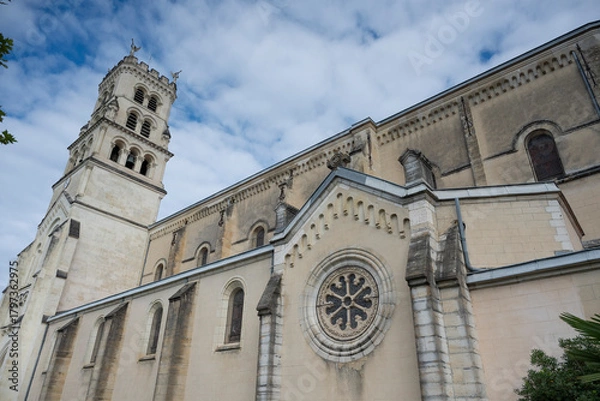 Fototapeta Explore the stunning architecture of the Basilica of Notre-Dame-de-Buglose, located in Saint-Vincent-de-Paul, Landes. The building showcases intricate designs against a moody sky.