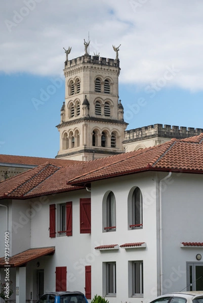 Fototapeta Explore the stunning architecture of the Basilica of Notre-Dame-de-Buglose, located in Saint-Vincent-de-Paul, Landes. The building showcases intricate designs against a moody sky.