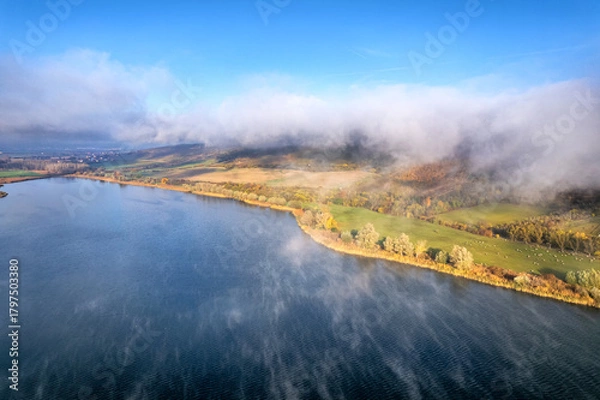 Obraz Nebelschwaden hängen am Hang eines Hügels an einem See fest