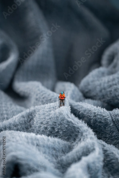 Fototapeta A mountaineer figurine on a fluffy fleece fabric that looks like a snow-covered mountain surface