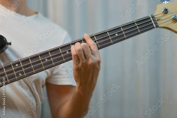 Fototapeta Close-up of hand fretting notes on an electric bass guitar
