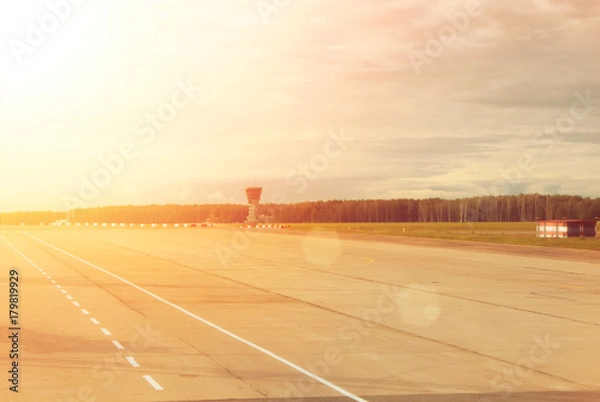 Fototapeta Airport runway with a forest at the background on cloudy day, toned background with copy space.