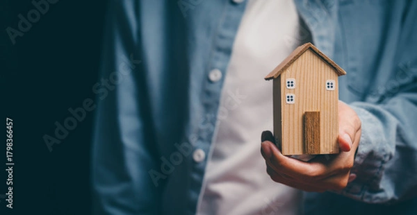 Fototapeta Hand holding wooden house, home security awareness, property protection stability, financial planning support, housing responsibility insight, reassurance and safe home value concept