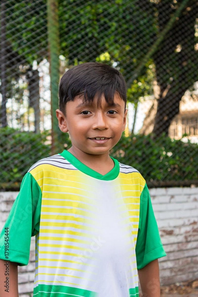 Fototapeta Portrait of a boy Colombian soccer player smiling and looking at the camera inside a sports club in Neiva, Huila, Colombia. Concept of childhood and happiness