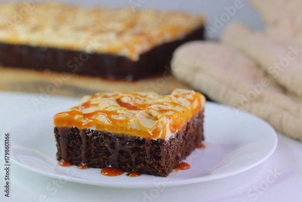 Fototapeta Moist chocolate cake slice topped with buttercream frosting and drizzled with caramel cream sauce.