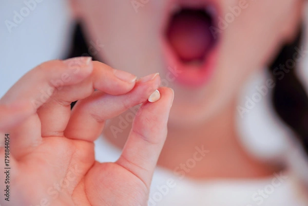 Obraz 歯が抜けた！初めての乳歯を見せる女の子のクローズアップ