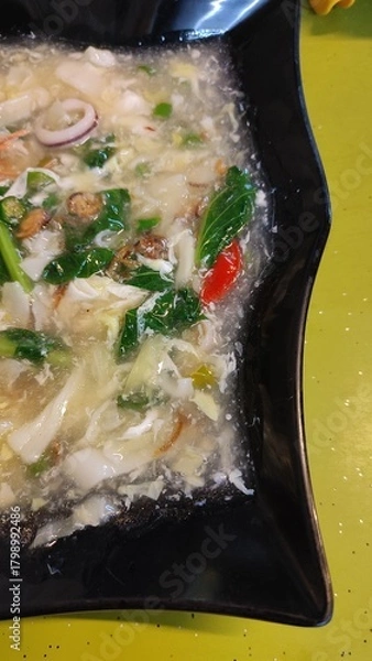 Fototapeta A close up half picture of Kuey Teow Kungfu with Egg and seafood  in a black plate