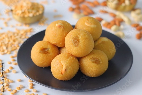Fototapeta Chana dal motichur laddus stacked on a black plate, garnished with dry fruits