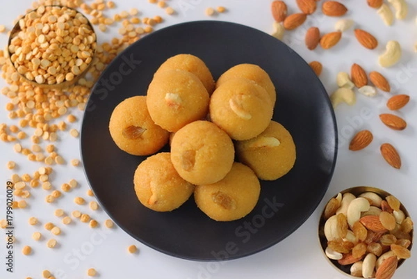 Fototapeta Chana dal motichur laddus stacked on a black plate, garnished with dry fruits