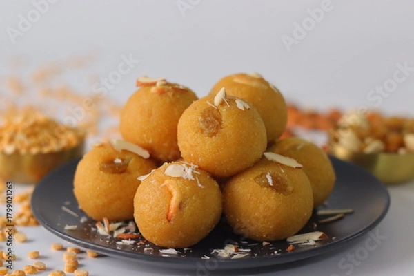 Fototapeta Chana dal motichur laddus stacked on a black plate, garnished with dry fruits