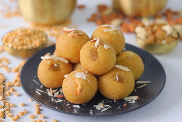 Fototapeta Chana dal motichur laddus stacked on a black plate, garnished with dry fruits