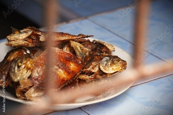 Obraz Crispy Fried Fish Platter Served on a White Plate with a Blurry Foreground.