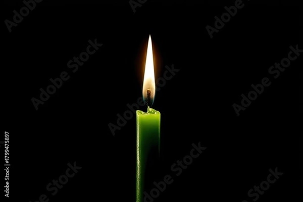 Fototapeta Single green candle flame burning brightly against a stark black background
