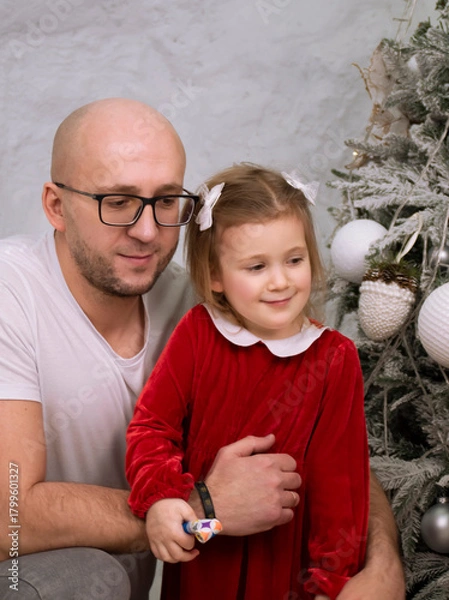 Fototapeta father and daughter happily playing and having fun near the Christmas tree