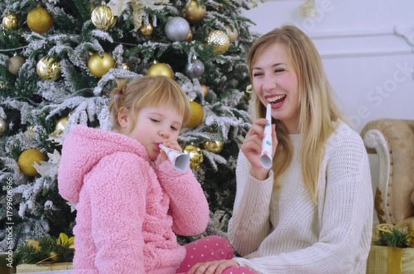 Fototapeta mom and daughter happily playing and having fun near the Christmas tree