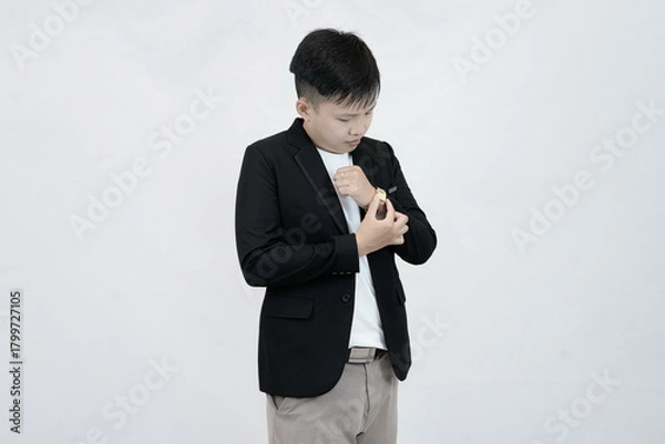 Fototapeta A focused young Asian professional adjusting a wristwatch on their sleeve, conveying a sense preparation, or time management against a clean white studio background