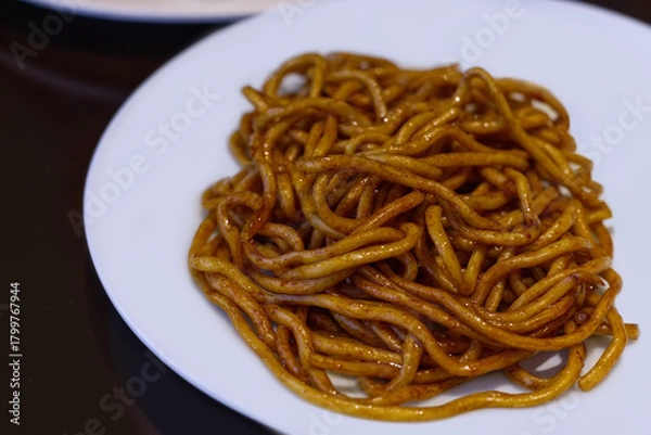 Fototapeta A close-up of thick, chewy Shanghai Fried Noodles coated in a rich, dark soy sauce. This simple, appetizing image represents a classic style of Chinese comfort food