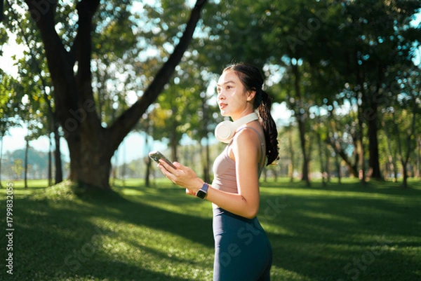 Obraz Young woman enjoying nature using phone in park