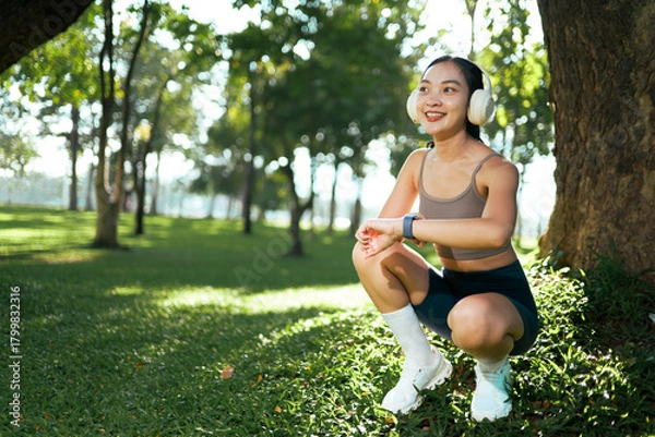 Obraz Woman exercising in park while checking smartwatch