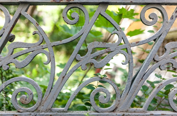 Obraz Close up of a grey railing with green leafs in background