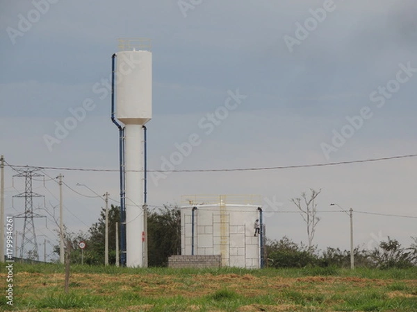 Fototapeta High voltage power lines and water tanks in the country