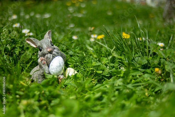 Fototapeta Easter bunny holding easter eggs. sitting in grass. Easter photo