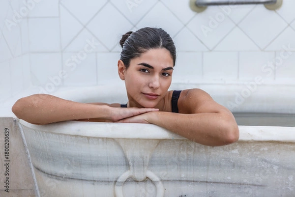 Fototapeta Woman relaxing in a bathtub at a hot spring spa, experiencing tranquility and wellness
