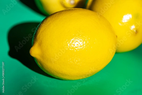 Fototapeta A bright yellow lemon placed on a clean table surface, captured in natural light. The simple composition highlights the vibrant color and fresh texture of the lemon, making it ideal for food photograp