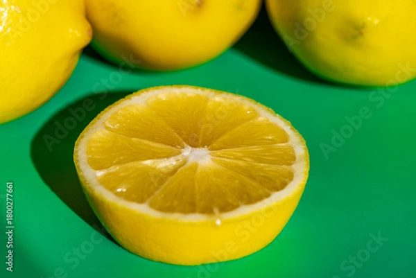 Fototapeta A vibrant yellow lemon resting on a table, captured in soft natural light. The image highlights the fruit’s bright color, fresh texture, and simple composition, making it suitable for food photography