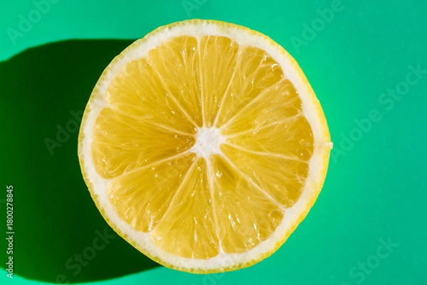 Fototapeta A vibrant yellow lemon resting on a table, captured in soft natural light. The image highlights the fruit’s bright color, fresh texture, and simple composition, making it suitable for food photography