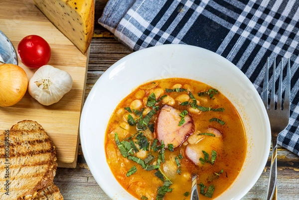 Fototapeta A hearty bowl of cooked bean stew with tender pieces of meat, served in a clean white dish. The warm, rich broth highlights the soft beans and juicy meat, while natural lighting 