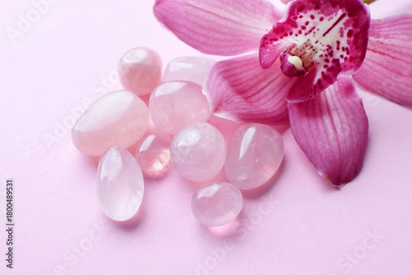 Obraz Natural rose quartz stones and a pink cymbidium orchid flower on a pink background. Healing crystals.