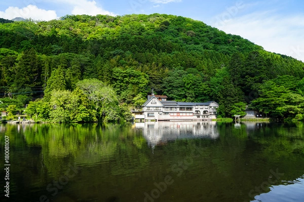 Obraz Beautiful abundant natural green mountain slope reflection on fresh lake Kinrinko with buildings during springtime