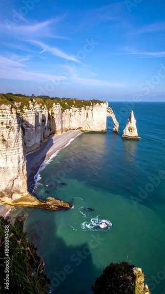 Obraz A coastal landscape featuring towering white cliffs, an archway, a pebbled beach, and crystal blue water under a bright sky