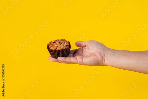 Fototapeta Toffee cake, a close up of homemade caramel nut chocolate cake bakery and hand isolated on yellow background.