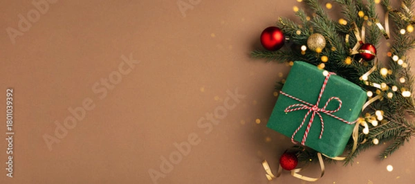 Obraz Christmas gift, fluffy fir branches, golden sparkling streamers and Christmas tree decorations, beige background