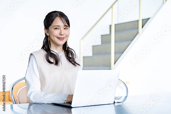 Fototapeta カフェまたは自宅のような明るい空間で、女性がノートパソコンの前に座り仕事をするシーン。