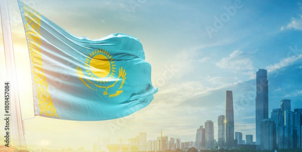 Fototapeta Kazakhstan flag wavering in beautiful clouds with building skyline. The flag with drone shot in beautiful sky. Kazakhstan national flag for independence day.