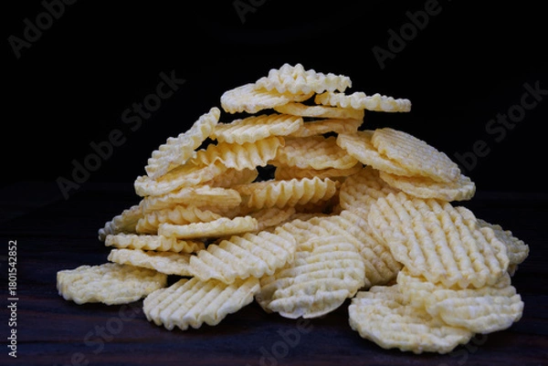 Fototapeta Round corn chips in a pile. Corrugated corn chips on a dark background.